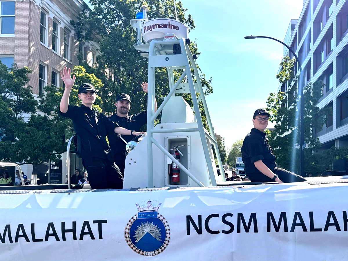 HMCS Malahat on parade: (L-R): Sailor 3rd Class (S3) Cooper Vasey, S3 Malcolm Rorvik, and S3 Callum Leblanc of HMCS Malahat wave to the crowds from aboard one of Malahat’s Rigid Hull Inflatable Boats during the 124th Thrifty Foods Victoria Day Parade in downtown Victoria, May 20. Photo: Lt(N) Donald Den.