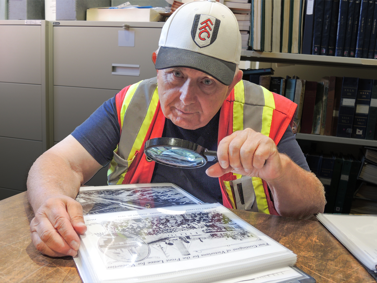 Le commissionnaire Gary Restell examine une photographie de 1914 représentant un défilé de soldats et de marins canadiens dans l’arsenal, dans les archives du musée naval et militaire de la BFC Esquimalt. Photos : Peter Mallett/Lookout Newspaper