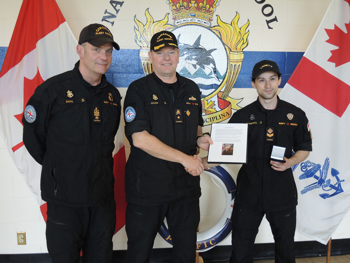 (À gauche) Le PM 1 David Bisal, chef de la Flotte, et le Commodore David Mazur, commandant/commandante de la Flotte canadienne du Pacifique, remettent au Matelot de 1re classe Nicholas Campbell son certificat de Matelot du trimestre lors d’une cérémonie tenue le 16 mai à l’École de la Flotte navale du Pacifique.