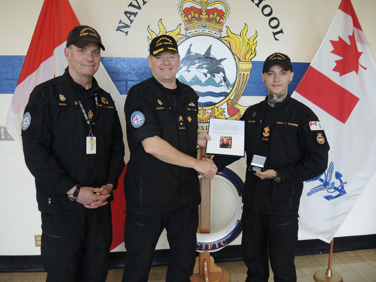 (À gauche) Le PM 1 David Bisal, chef de la flotte, et le Commodore David Mazur, commandant/commandante de la Flotte canadienne du Pacifique, remettent au matelot-chef Tristan Harris son certificat de marin du trimestre lors d’une cérémonie qui s’est déroulée le 16 mai à l’École de la Flotte navale du Pacifique.