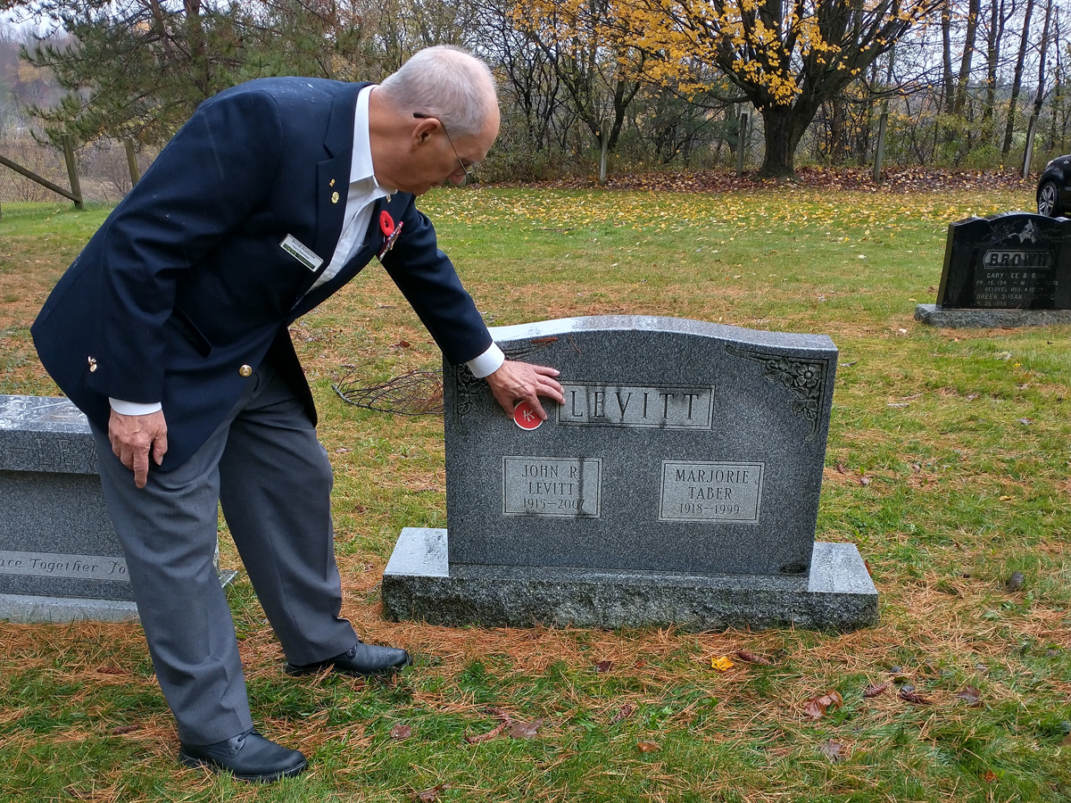 Derrill Henderson, bénévole de l'Association commémorative des anciens combattants de Hong Kong, montre le marqueur " HK " qui est ajouté aux pierres tombales partout au Canada, y compris celle de John Levitt, membre du 1er Bataillon, The Royal Rifles of Canada Canadian Active Service Force (CASF), à Trenholm, au Québec.